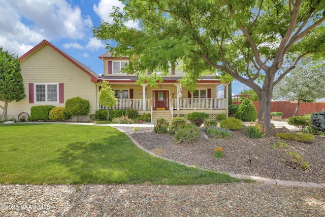 view of front facade with a front yard, covered porch, and fence