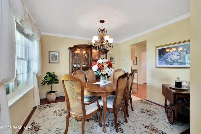 dining room featuring baseboards, a chandelier, light wood-style floors, and crown molding