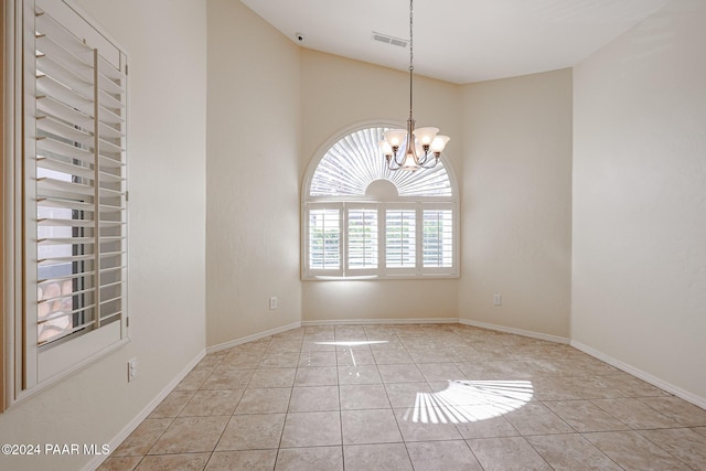 tiled spare room with vaulted ceiling and an inviting chandelier