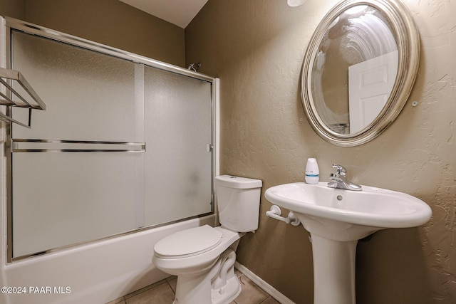 bathroom featuring tile patterned flooring, toilet, and combined bath / shower with glass door