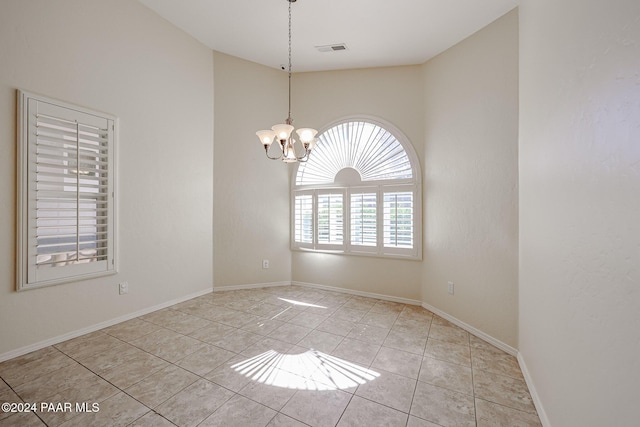 tiled empty room featuring vaulted ceiling and an inviting chandelier