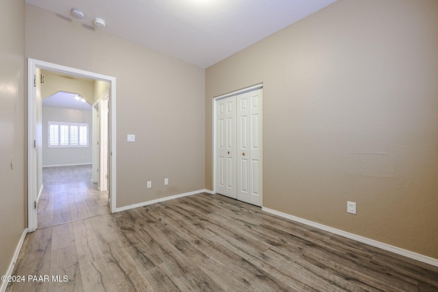 unfurnished room featuring light hardwood / wood-style floors and lofted ceiling