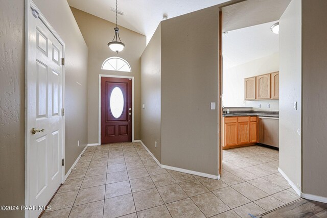 entryway with high vaulted ceiling and light tile patterned floors