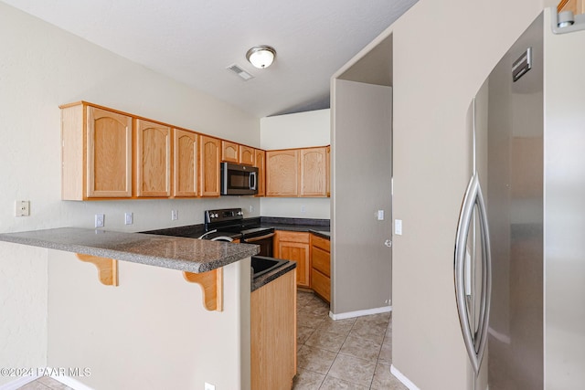 kitchen featuring a kitchen bar, kitchen peninsula, stainless steel appliances, and light tile patterned floors