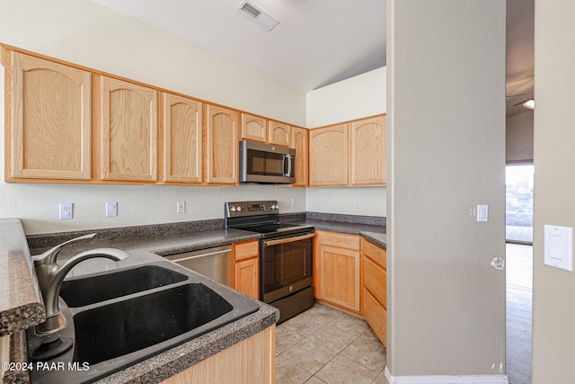 kitchen with appliances with stainless steel finishes, sink, light brown cabinets, light tile patterned floors, and lofted ceiling