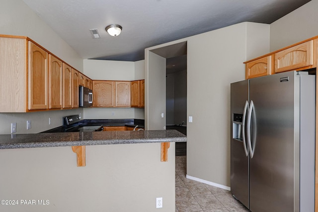 kitchen with kitchen peninsula, stainless steel appliances, a breakfast bar area, and light tile patterned flooring