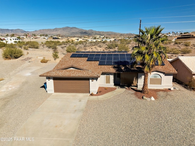 view of front of home with a garage, a mountain view, and solar panels