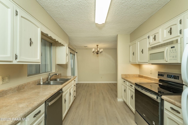 kitchen with a sink, light wood-type flooring, white cabinetry, a notable chandelier, and appliances with stainless steel finishes
