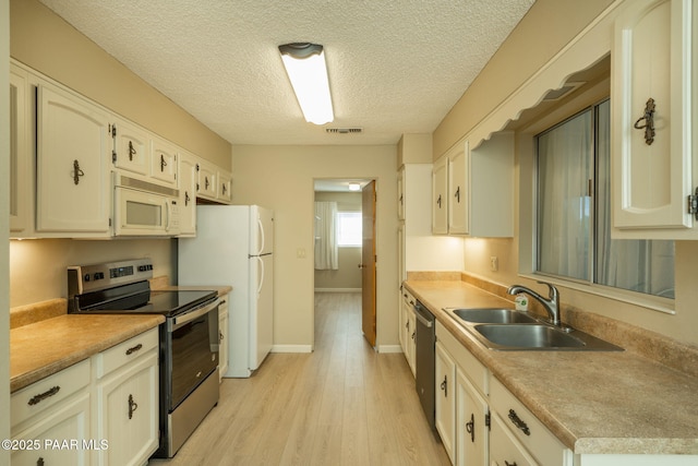 kitchen with light countertops, visible vents, a sink, light wood-style floors, and appliances with stainless steel finishes