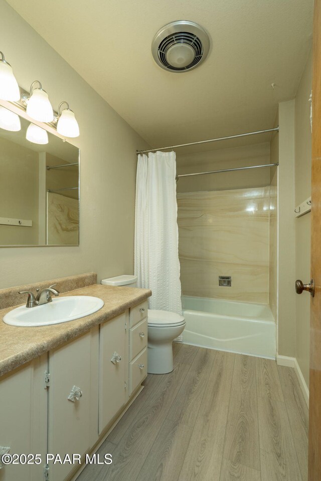 full bathroom featuring wood finished floors, visible vents, toilet, vanity, and shower / tub combo with curtain