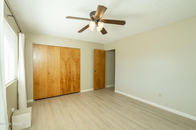unfurnished bedroom with baseboards, wood finished floors, a textured ceiling, and a closet