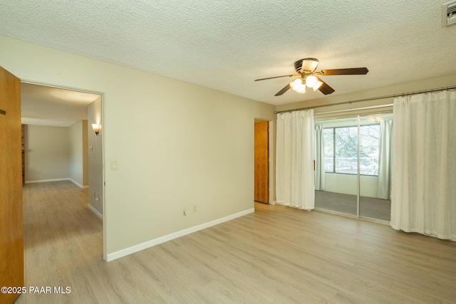 unfurnished room featuring baseboards, a ceiling fan, a textured ceiling, and light wood finished floors