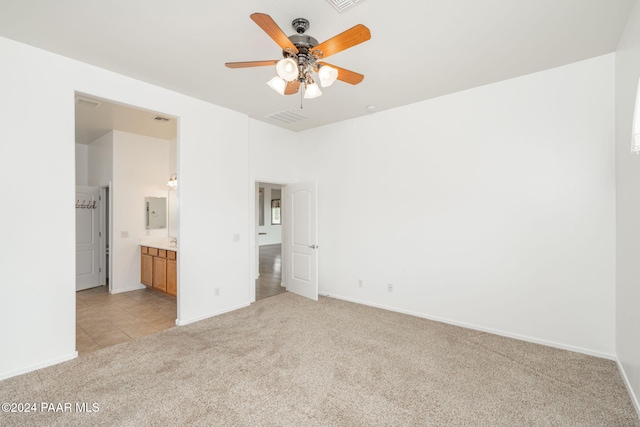 unfurnished bedroom with light carpet, ensuite bathroom, and ceiling fan