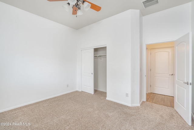 unfurnished bedroom featuring ceiling fan, light colored carpet, and a closet