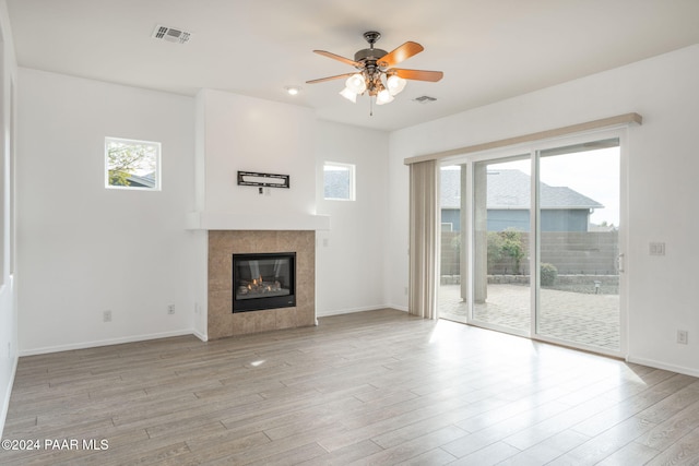 unfurnished living room featuring ceiling fan, light hardwood / wood-style floors, and a tile fireplace