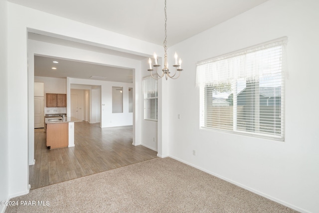 empty room with light wood-type flooring and a notable chandelier