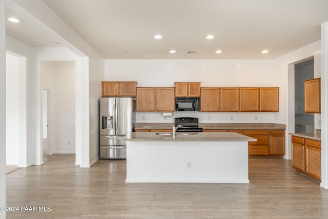 kitchen with sink, an island with sink, light hardwood / wood-style floors, and black appliances