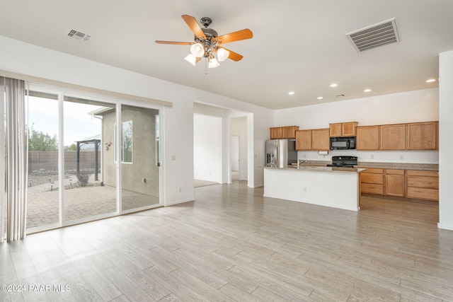 kitchen featuring a kitchen island with sink, black appliances, sink, light hardwood / wood-style flooring, and ceiling fan