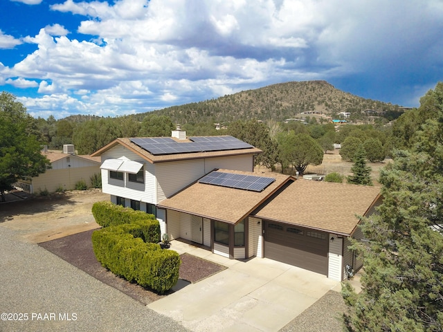 3035 Hozoni Rd, Prescott, AZ 86305 - view of front of home featuring a mountain view, a shingled roof, roof mounted solar panels, concrete driveway, and a garage