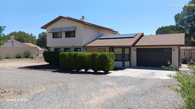 3035 Hozoni Rd, Prescott, AZ 86305 - tri-level home with driveway, a garage, roof mounted solar panels, a chimney, and a shingled roof