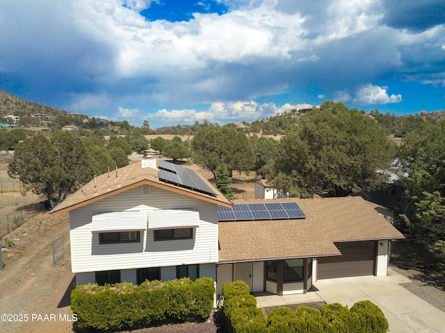 3035 Hozoni Rd, Prescott, AZ 86305 - view of front facade with a shingled roof, roof mounted solar panels, concrete driveway, and a garage