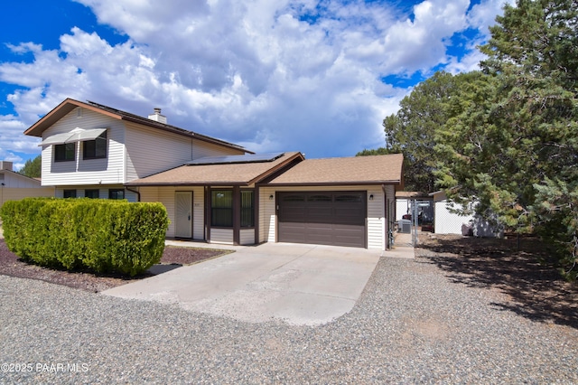 3035 Hozoni Rd, Prescott, AZ 86305 - tri-level home featuring a garage, concrete driveway, roof mounted solar panels, a chimney, and a gate