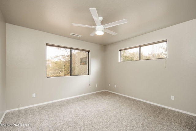 carpeted spare room with visible vents, baseboards, and ceiling fan