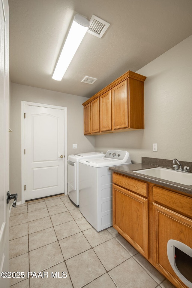 laundry area with visible vents, a sink, light tile patterned floors, cabinet space, and separate washer and dryer