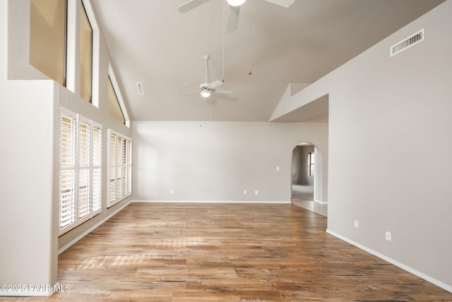 empty room featuring visible vents, high vaulted ceiling, wood finished floors, arched walkways, and ceiling fan