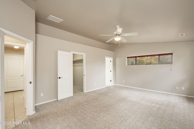 unfurnished bedroom featuring a spacious closet, visible vents, and light carpet