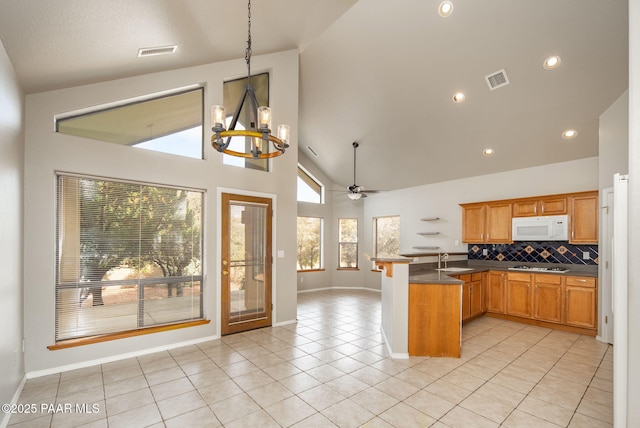 kitchen with visible vents, tasteful backsplash, a peninsula, light tile patterned floors, and white microwave