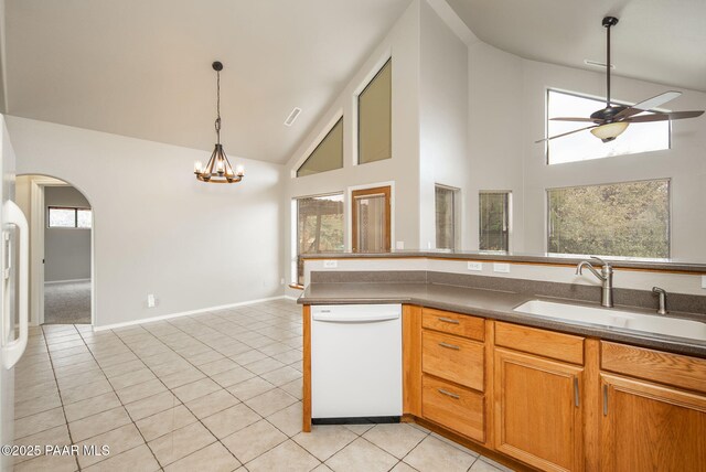 kitchen with ceiling fan with notable chandelier, a sink, arched walkways, light tile patterned floors, and dishwasher