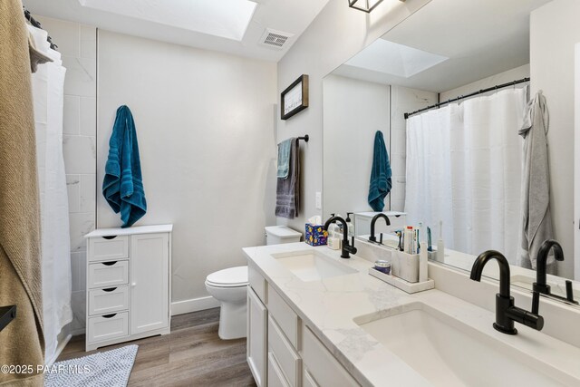 4714 N Sheridan Ln, Prescott Valley, AZ 86314 - full bath featuring wood finished floors, a skylight, double vanity, and toilet