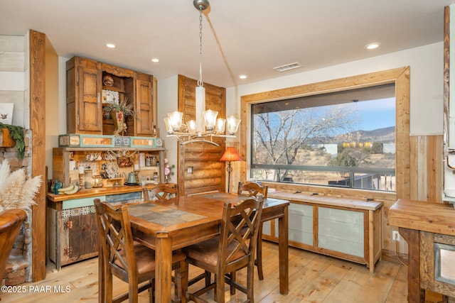 dining space with log walls, light hardwood / wood-style flooring, and a notable chandelier