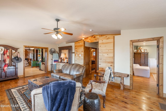 living area featuring lofted ceiling, light wood-style flooring, visible vents, and ceiling fan