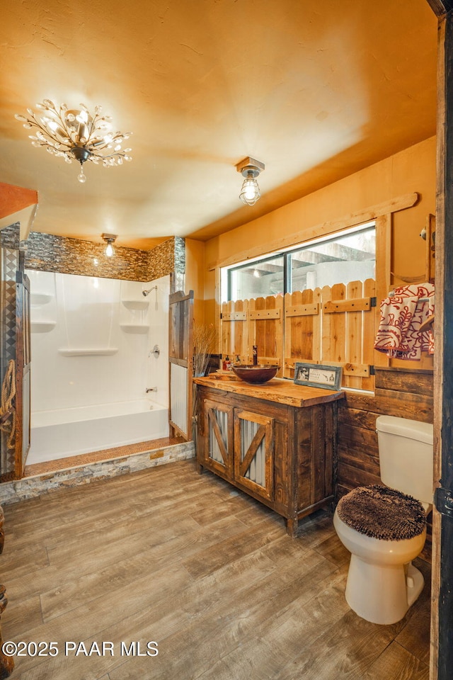 full bathroom with washtub / shower combination, toilet, vanity, and wood finished floors