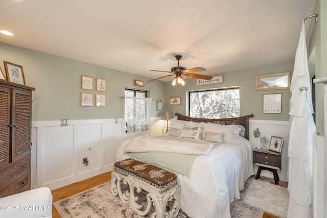 bedroom featuring a wainscoted wall, a ceiling fan, and light wood finished floors