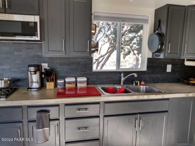 kitchen with tasteful backsplash, gray cabinetry, and sink