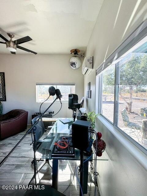 interior space with hardwood / wood-style floors, a wall mounted AC, and ceiling fan