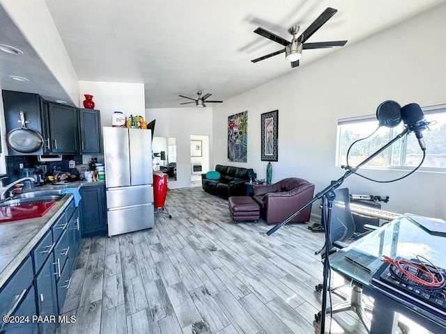 kitchen featuring stainless steel fridge, light hardwood / wood-style flooring, ceiling fan, and sink