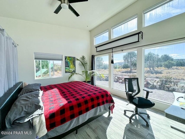 bedroom with multiple windows, ceiling fan, and light wood-type flooring