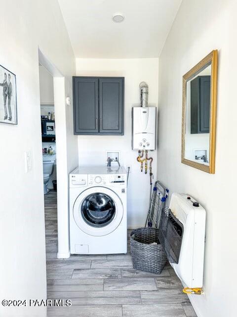 laundry room with cabinets, tankless water heater, washer / clothes dryer, heating unit, and light wood-type flooring