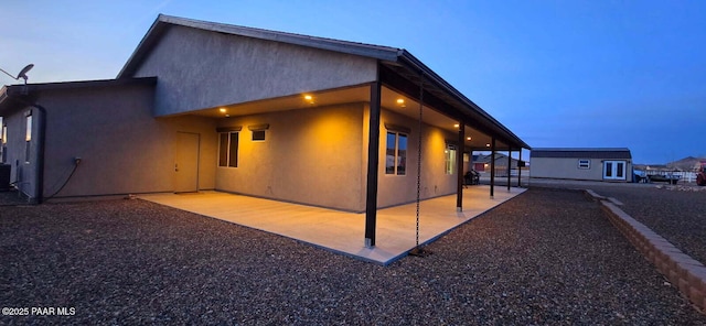 property exterior at dusk with an outdoor structure, cooling unit, and a patio area