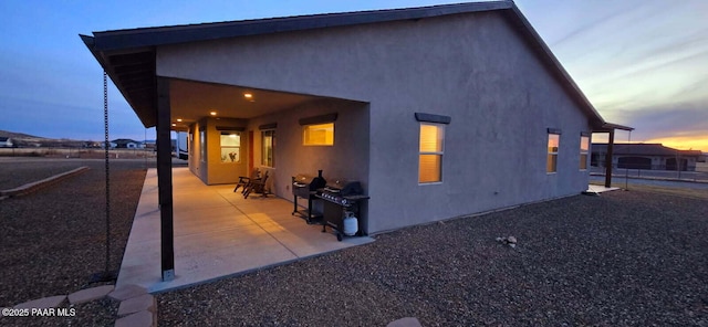 property exterior at dusk featuring a patio area