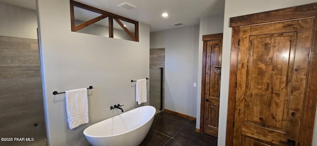 bathroom with a tub to relax in and tile patterned flooring