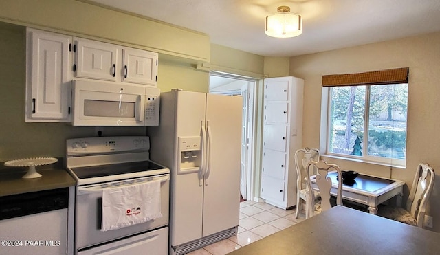 kitchen with dark countertops, white appliances, white cabinets, and light tile patterned flooring