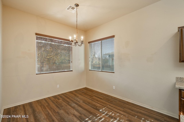 unfurnished dining area featuring a notable chandelier and dark wood-type flooring