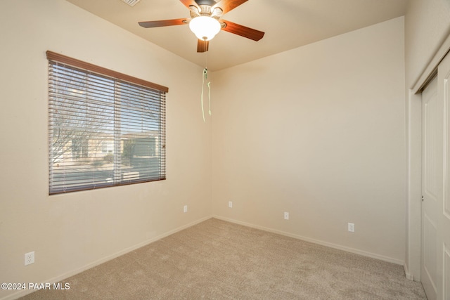 unfurnished bedroom with a closet, light colored carpet, and ceiling fan