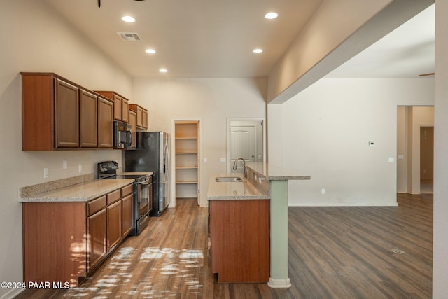 kitchen with black electric range, dark hardwood / wood-style floors, light stone counters, and sink