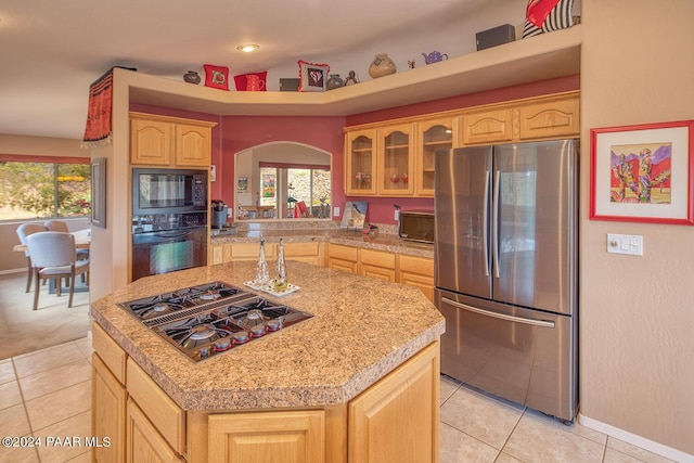 kitchen with black appliances, a kitchen island, light tile patterned floors, and light brown cabinets